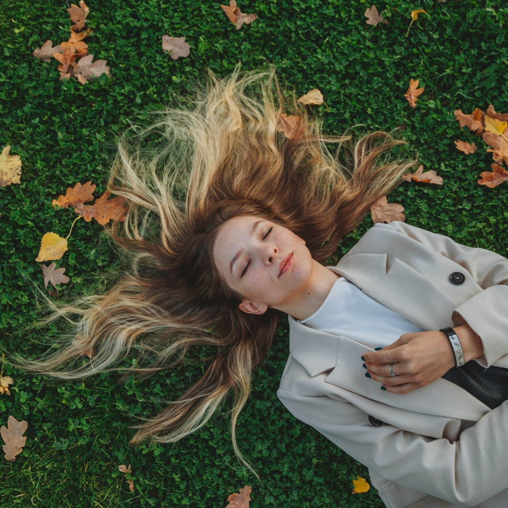 Blonde Frau liegt auf Gras mit Herbstblättern